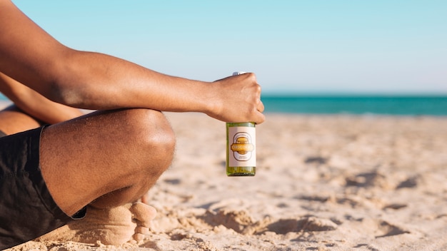 Uomo con il modello di bottiglia di birra in spiaggia