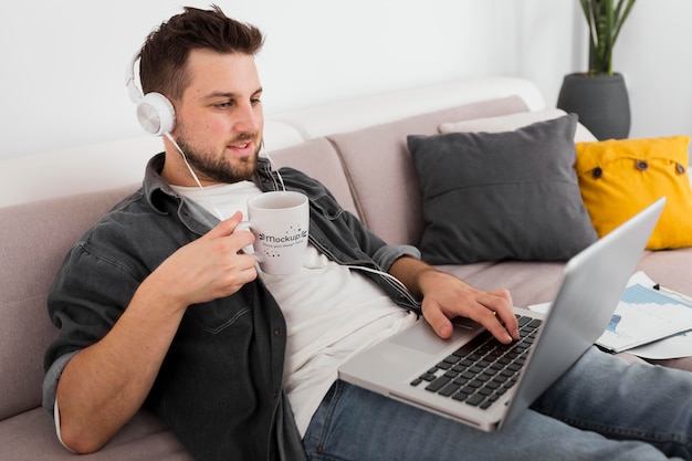 PSD man with laptop drinking from mug mock-up