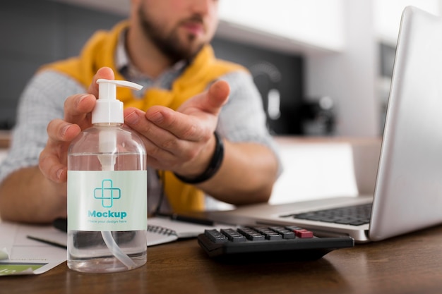 Uomo con laptop utilizzando disinfettante mock-up