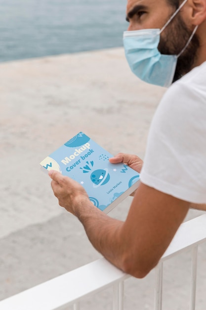 PSD man with mask on street reading book