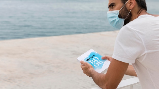 man with mask on street reading book