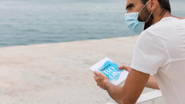 PSD man with mask on street reading book