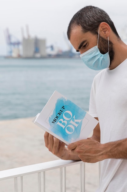 man with mask on street reading book