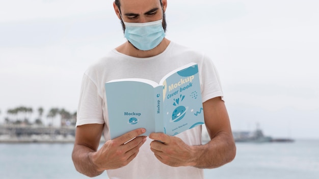 Man with mask on street reading book