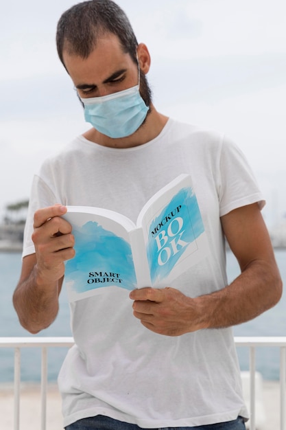 Man with mask on street reading book