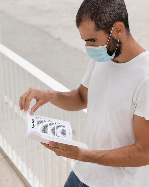 PSD man with mask on street reading book