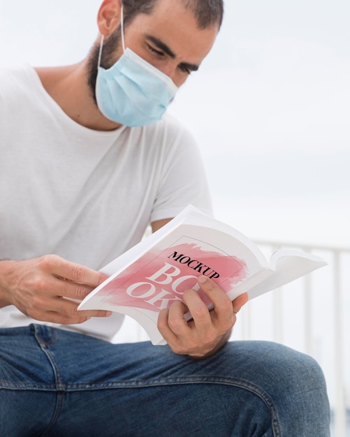 man with mask on street reading book