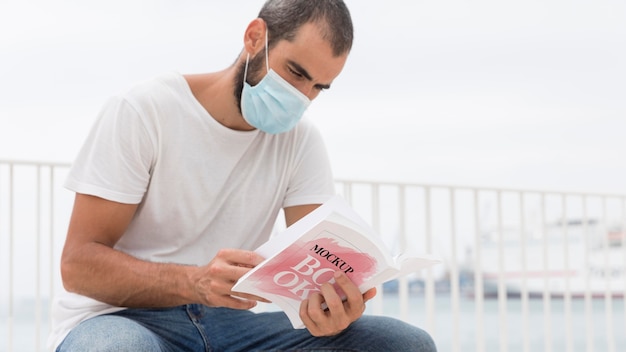 man with mask on street reading book