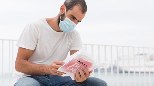 Uomo con la maschera sul libro di lettura di strada