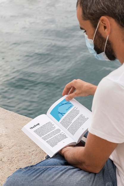 man with mask on street reading book