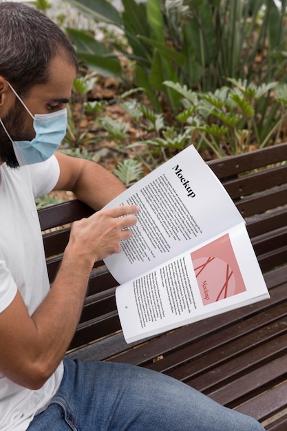 PSD man with mask on street reading book