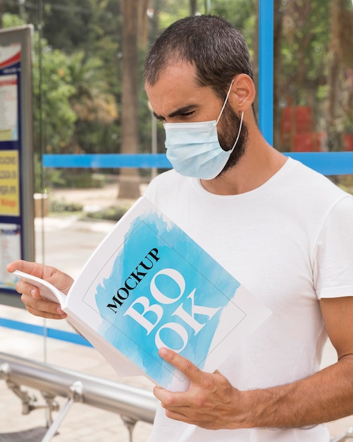 man with mask on street reading book
