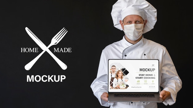 PSD medium shot chef with mask holding laptop