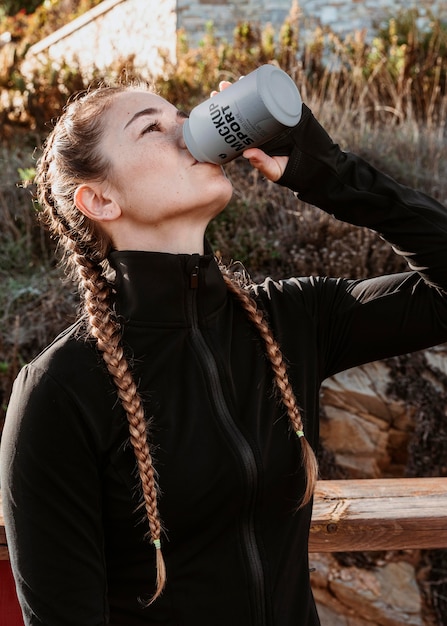 Medium shot woman drinking from can