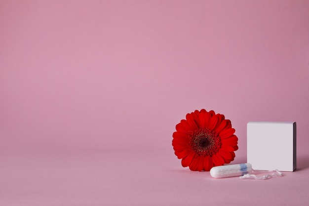 PSD menstrual tampons and red flower isolated on pink table, top view. copy space