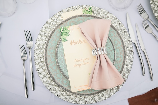 Menu card mockup on laid table decorated with textile napkin