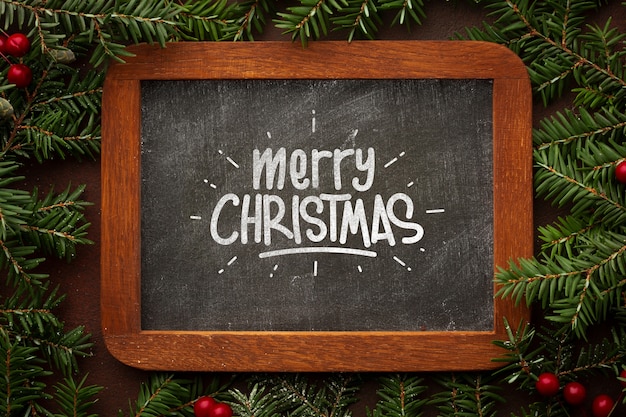 Merry christmas on chalkboard and christmas pine leaves