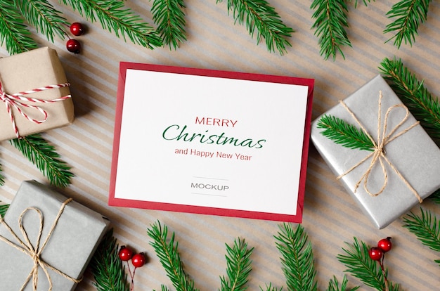 Merry christmas greeting card mockup with gift boxes and green fir tree branches