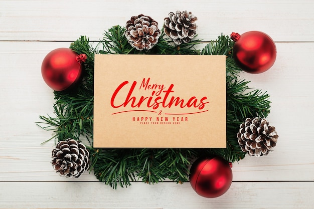 Mockup di biglietto di auguri di buon natale con decorazioni di foglie di pino