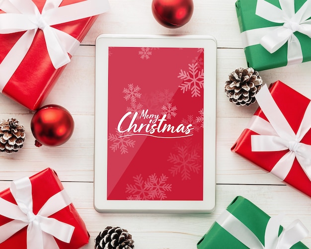 Mockup di computer tablet di buon natale con decorazioni di foglie di pino