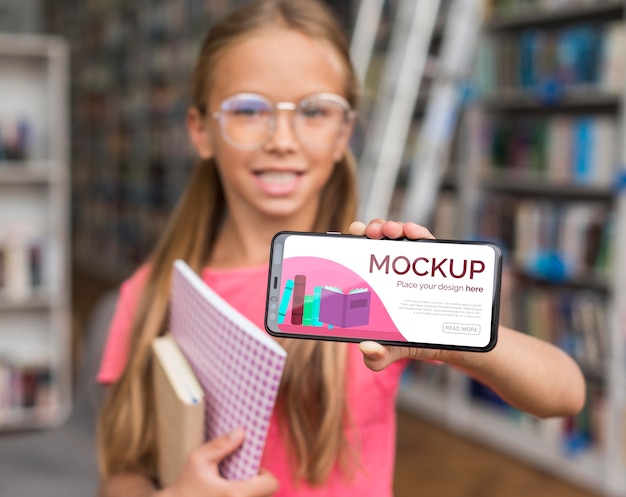 PSD mid shot girl in library showing mock-up phone