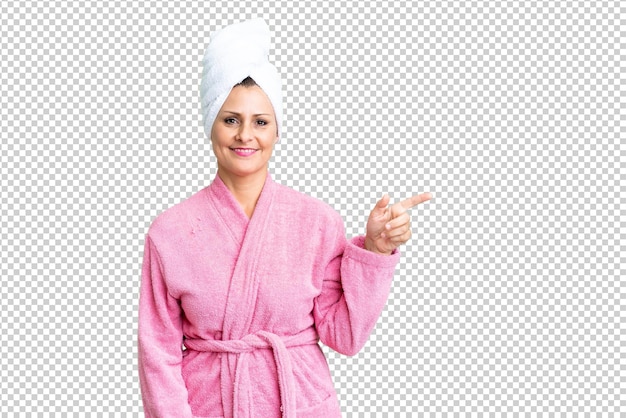 PSD middle age caucasian woman in a bathrobe over isolated background pointing finger to the side