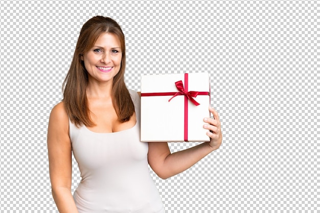 Middle age caucasian woman holding a gift over isolated background smiling a lot