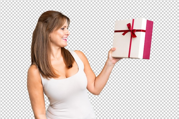 PSD middle age caucasian woman holding a gift over isolated background with happy expression