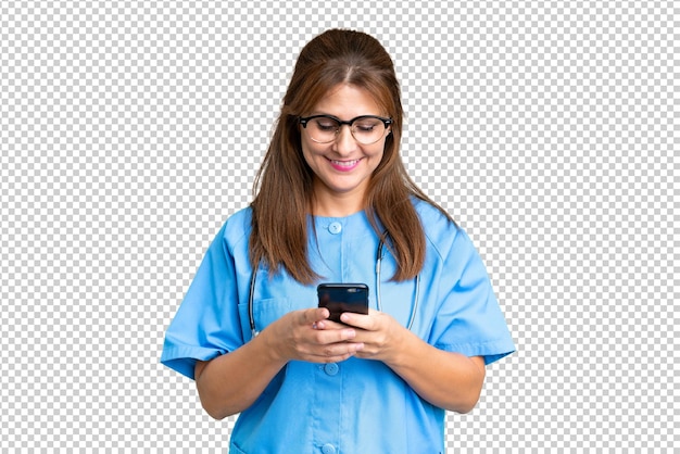 Middle age nurse woman over isolated background sending a message with the mobile