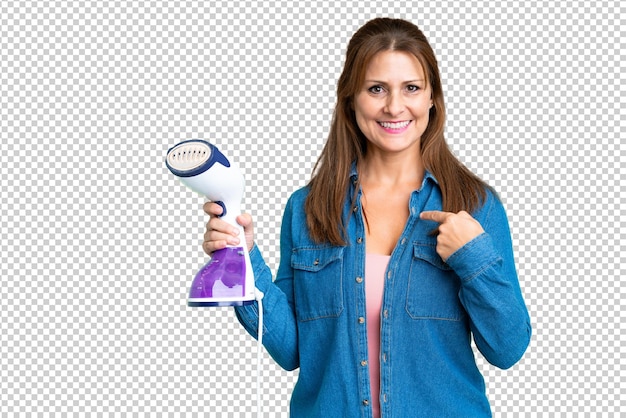 PSD middle age woman holding an iron over isolated background with surprise facial expression