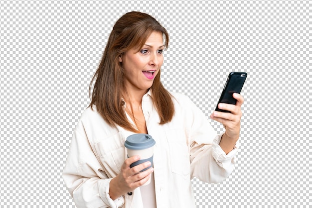 Middle age woman over isolated background holding coffee to take away and a mobile