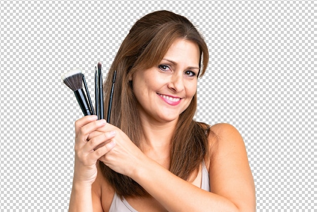 PSD middle age woman over isolated background holding makeup brush and whit happy expression