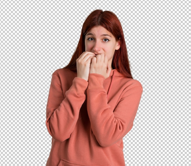 PSD młoda ruda dziewczyna z różową bluzą jest trochę nerwowa i przestraszona, wkładając ręce do ust