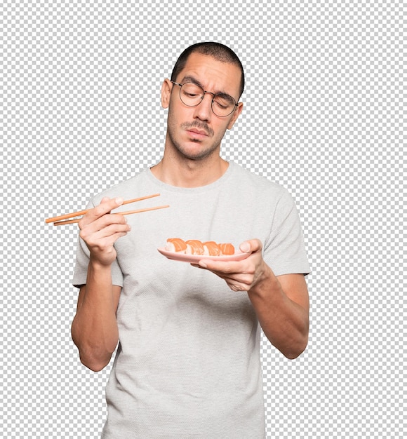 Młody człowiek za pomocą pałeczek do jedzenia sushi