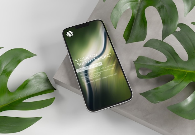 Mobile phone on concrete display with leaves mockup