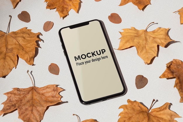 PSD mobile phone mockup on the table surrounded by leaves