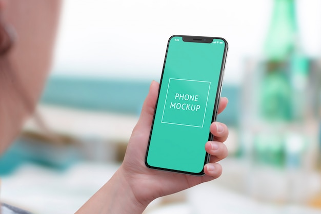 mobile phone mockup in woman hand. view above shoulder. modern smart phone with round edges