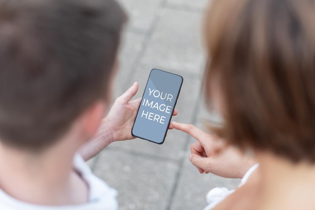 Mock up uomo e donna con in mano un telefono cellulare in cui puoi includere l'immagine di tua scelta