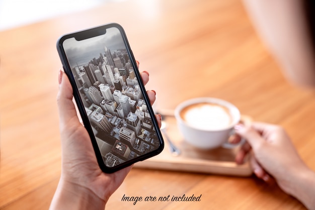 PSD mock up of smartphone in womans hand in coffee shop