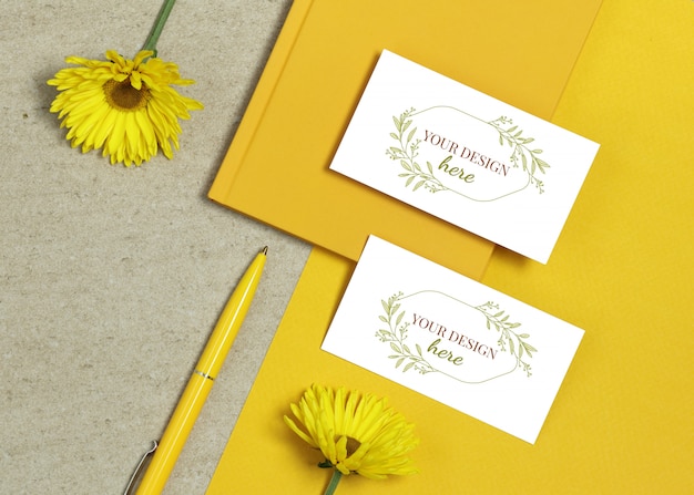 Mockup business card with book, yellow pen and summer flowers