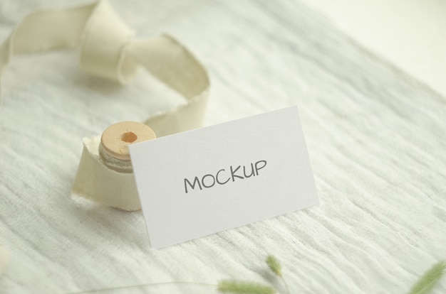 Mockup business card with herbs, vintage spool of cotton braid, on a light space