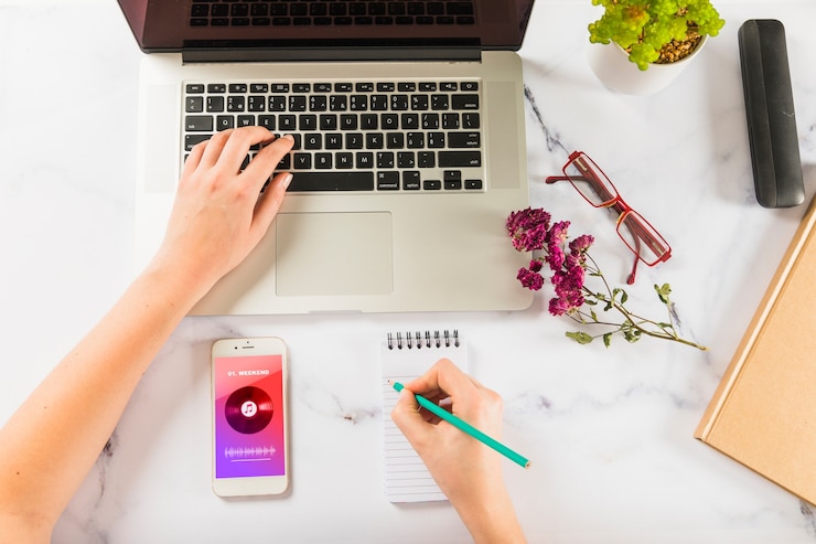 PSD mockup of hand writing on notepad with laptop and smartphone