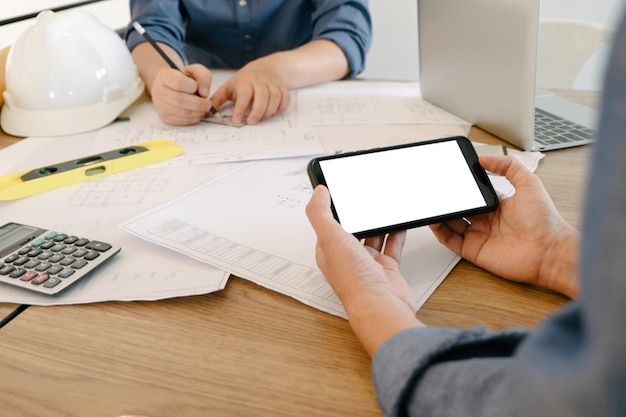 Mockup image of engineers using smartphone to drawing design Project in office