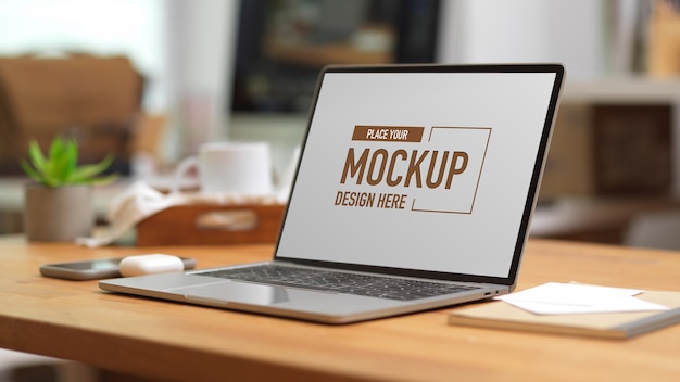 Computer portatile mockup sulla tavola di legno con forniture per ufficio e cancelleria