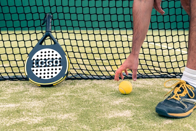 Mockup di una racchetta padel con monitor professionista che tiene una palla gialla