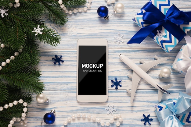 Smartphone con schermo mockup con modello di aereo tra le decorazioni natalizie