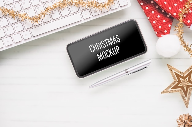 クリスマスと新年のホームオフィスの机の上のモックアップスマートフォン