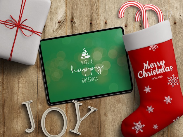 Mockup of tablet screen and stocking sock with Christmas decoration on wooden table