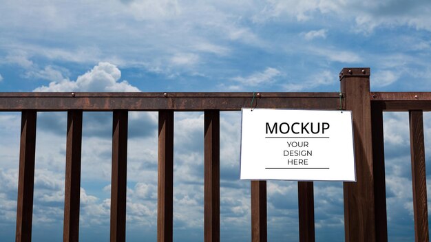 Mockup van teken op hek met cumuluswolken en blauwe lucht Billboard mockup