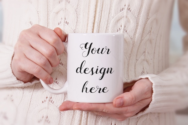 Mockup of a white coffee mug in woman's hands